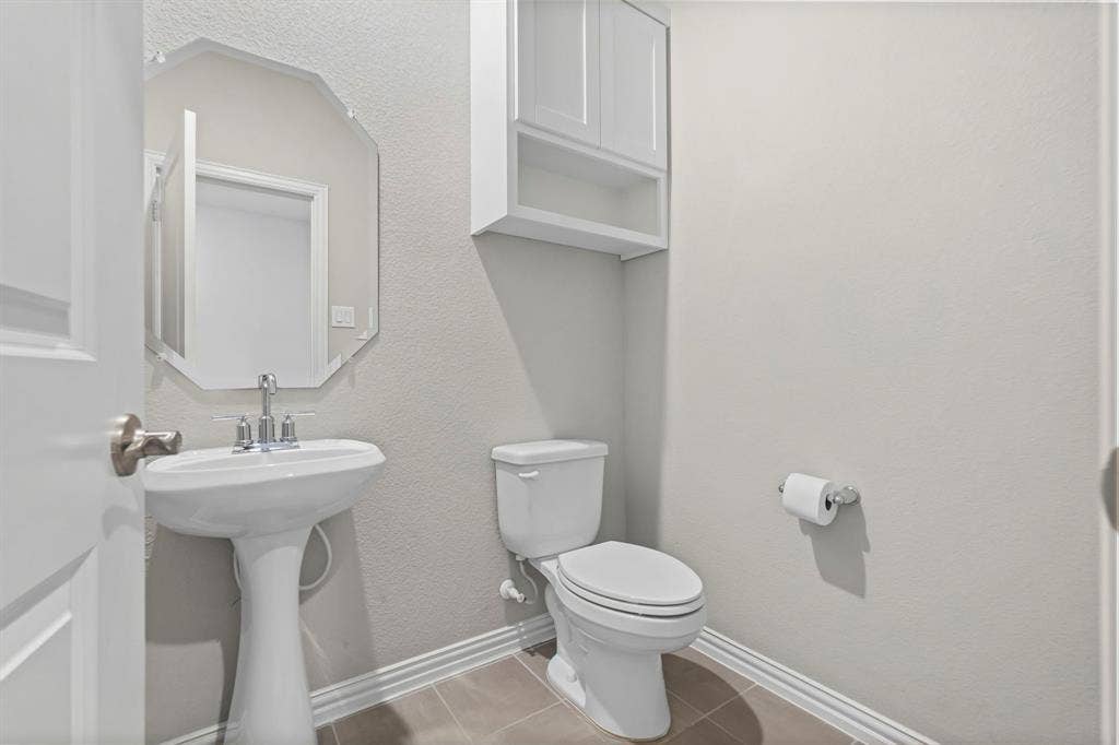 Pedestal sink with chrome faucet, geometric mirror, and wall-mounted cabinetry
