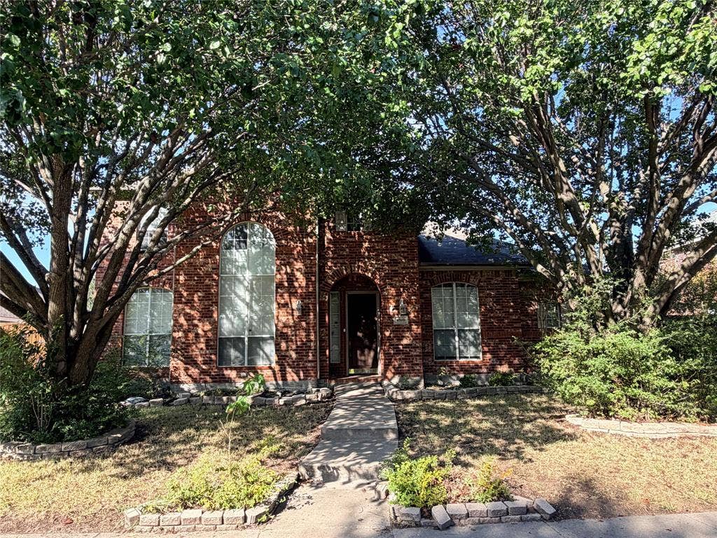 Charming brick residence featuring a classic single-story design with mature tree landscaping, manicured front lawn, and defined hardscape borders