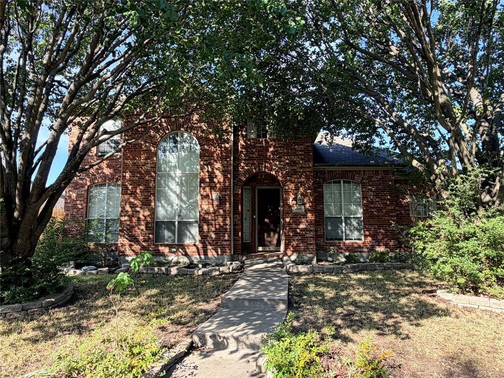 Charming brick residence framed by mature trees and lush landscaping