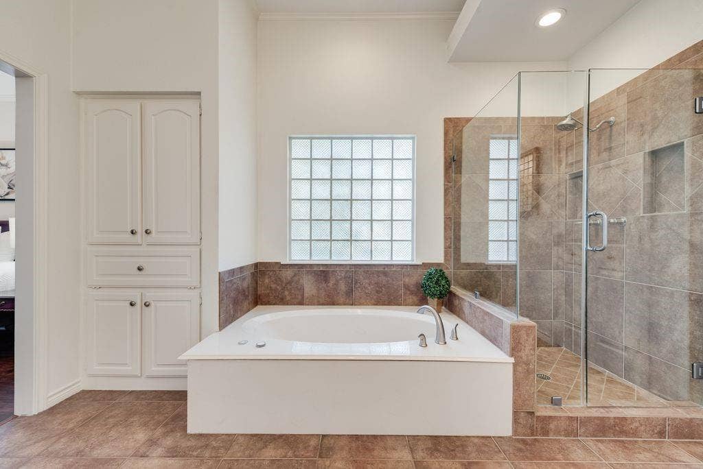 Primary suite includes large spa bath and glass enclosed glass shower, linen cabinet, two vanities, walk in closet.