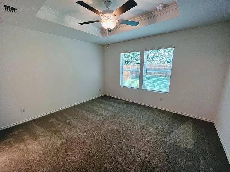 610 Grenada Lake Drive, Princeton, TX 75407 Tray ceiling with crown molding, ceiling fan with integrated lighting, recessed lighting, and two windows with blinds
