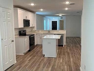 610 Grenada Lake Drive, Princeton, TX 75407 Kitchen featuring an island, white cabinetry with dark hardware, a stainless steel sink, black appliances, and wood-finish flooring