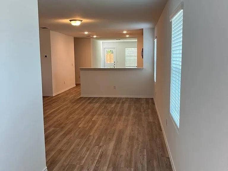 610 Grenada Lake Drive, Princeton, TX 75407 Wood-finish flooring throughout, multiple windows with blinds, recessed lighting, and a white interior paint scheme