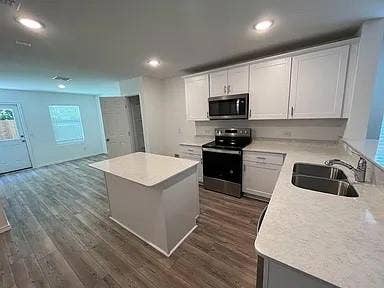 610 Grenada Lake Drive, Princeton, TX 75407 Kitchen featuring an island, stainless steel appliances, wood-finish flooring, white cabinetry, and recessed lighting