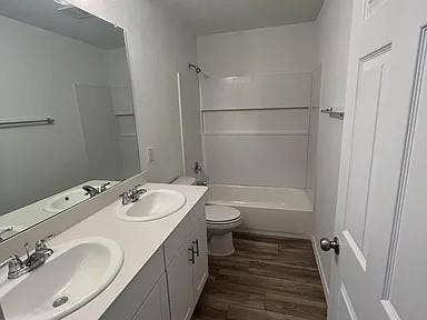 610 Grenada Lake Drive, Princeton, TX 75407 Dual vanity with integrated sinks, wood-finish flooring, and a shower-over-tub combination with a white surround