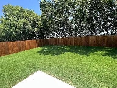 610 Grenada Lake Drive, Princeton, TX 75407 Expansive backyard with a manicured lawn, wood privacy fence, and mature trees