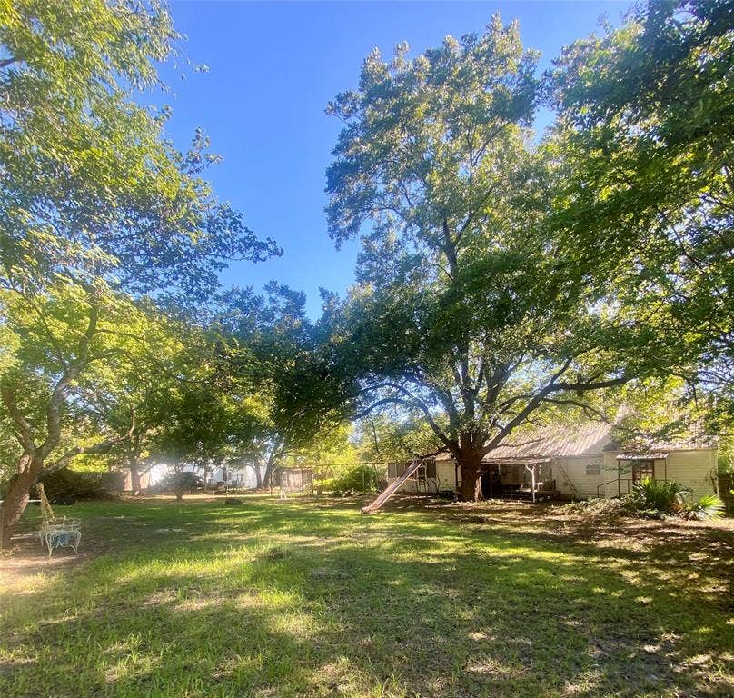 Expansive yard with mature trees providing ample shade and a grass lawn