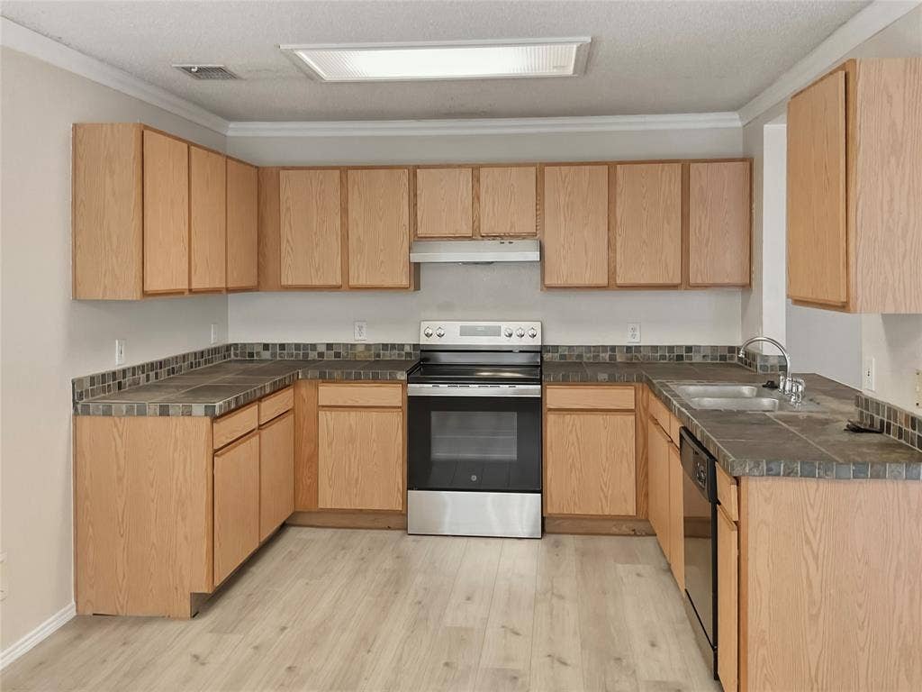 U-shaped kitchen layout featuring wood-finish cabinetry, tile countertops, and a tile backsplash