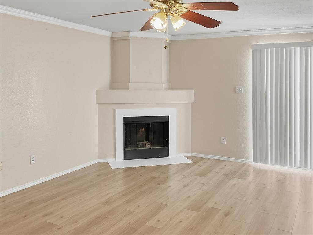 Fireplace with a white mantel, wood-finish flooring, ceiling fan with integrated lighting, and vertical blinds