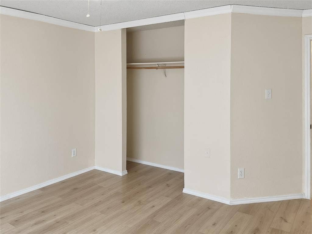 Wood-finish flooring, neutral wall color, and crown molding