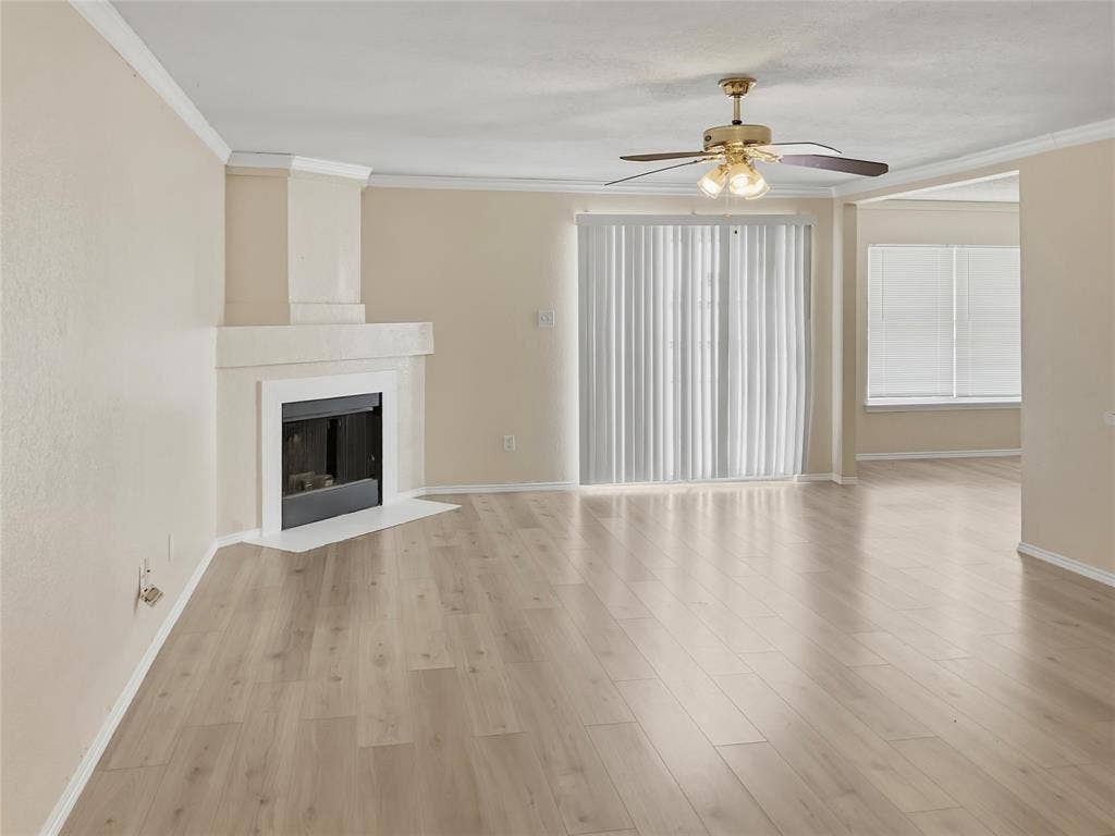 Contemporary fireplace with a hearth, wood-finish flooring, ceiling fan, and crown molding