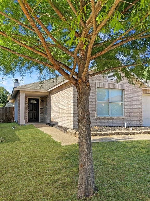 Charming brick residence with manicured lawn and mature shade tree