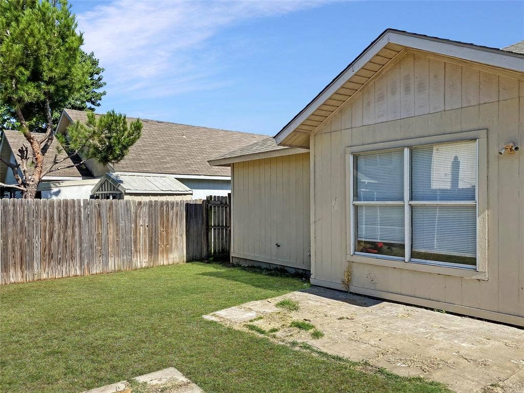 Spacious backyard with mature landscaping and manicured lawn, bordered by wooden fencing