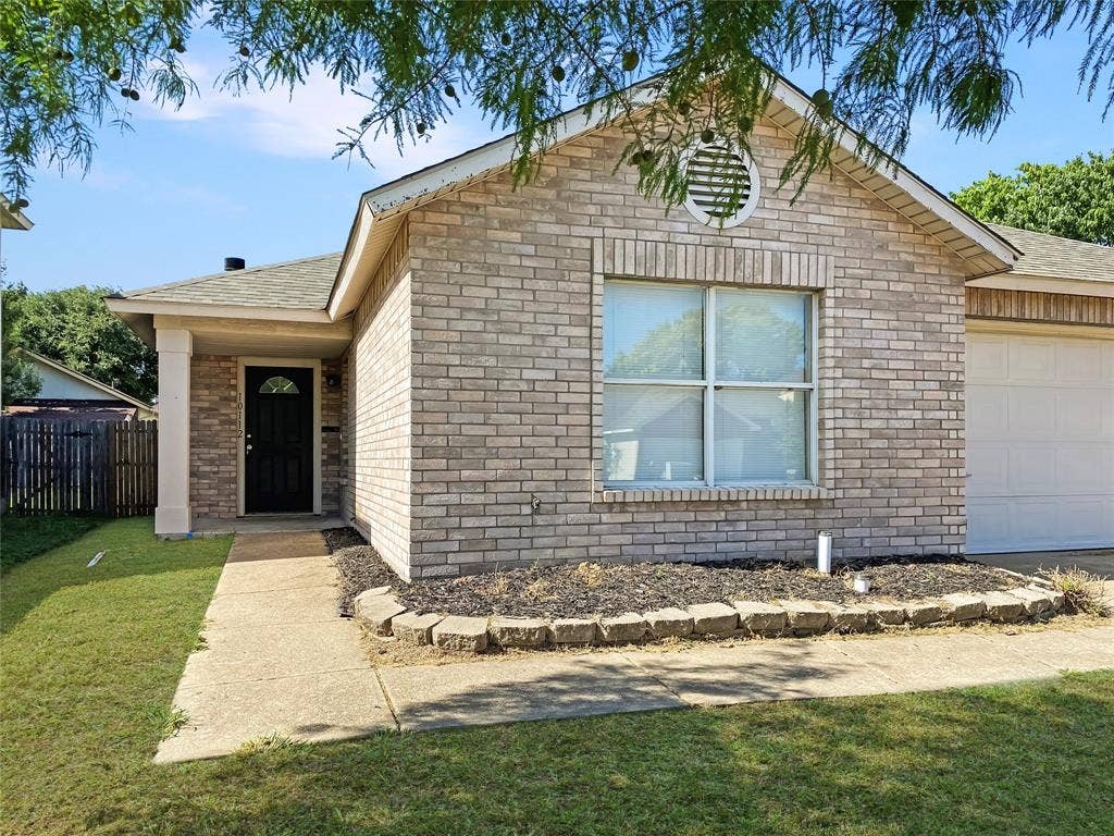 Brick exterior with a covered entry, an attached garage, and a landscaped front yard