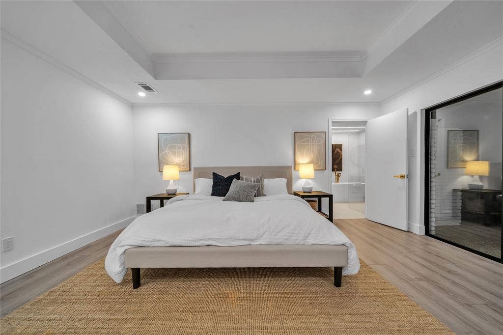 7001 Rocky Top Circle, Dallas, TX 75252 Bedroom featuring a raised ceiling, light wood-type flooring, ensuite bath, and ornamental molding