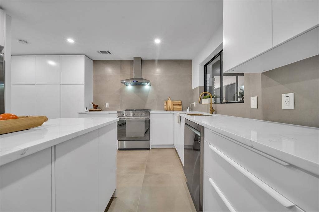 7001 Rocky Top Circle, Dallas, TX 75252 Kitchen featuring white cabinets, appliances with stainless steel finishes, wall chimney exhaust hood, and sink