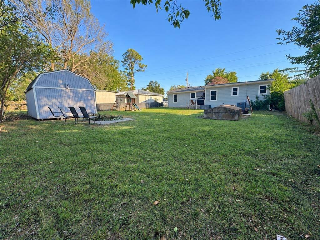 2611 Horne Circle, Caddo Mills, TX 75135 Expansive backyard featuring a manicured lawn, a detached storage shed, a paved patio, and a privacy fence