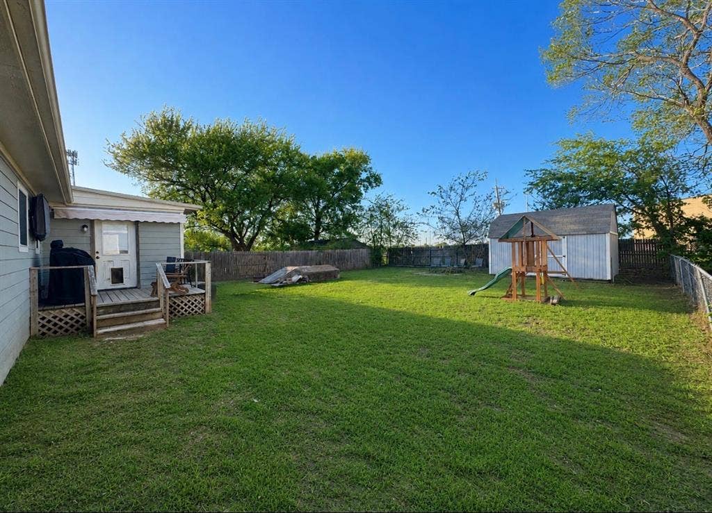 2611 Horne Circle, Caddo Mills, TX 75135 Expansive backyard featuring a manicured lawn, wood-constructed deck, and a white storage shed