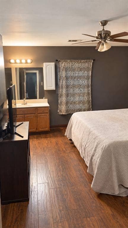 1017 W 3rd Street, Taylor, TX 76574 Comfortable master suite setup highlighting warm wood-look flooring and ceiling fan.