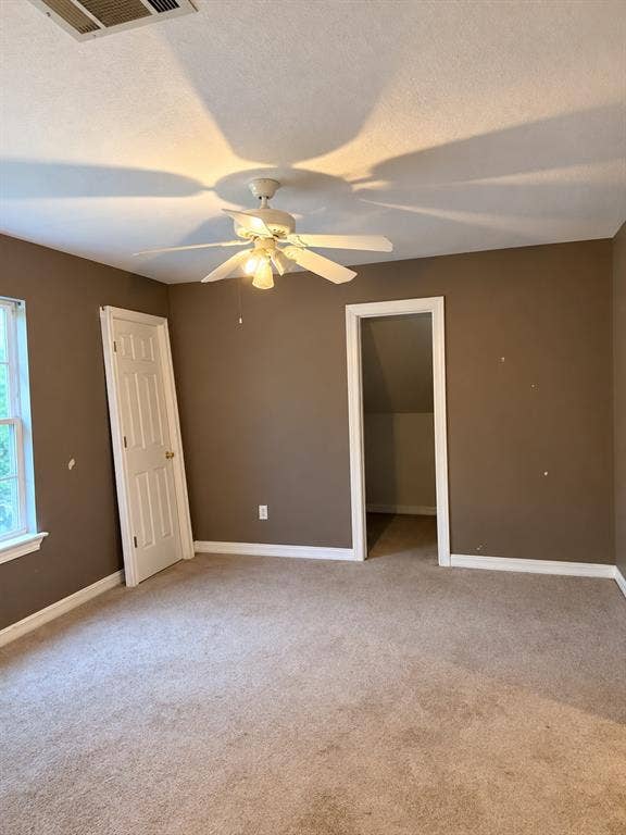 1017 W 3rd Street, Taylor, TX 76574 Generously sized bedroom with light neutral walls, bright window lighting, and plush carpeting.
