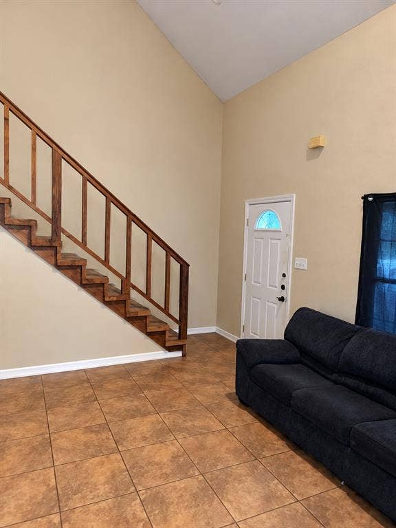 1017 W 3rd Street, Taylor, TX 76574 Dedicated entry space featuring soaring vaulted ceilings, open stairs, and direct living room access.