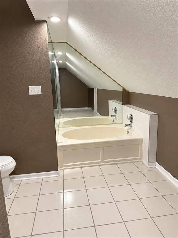 1017 W 3rd Street, Taylor, TX 76574 Primary bathroom suite boasting a deep soaking tub tucked under a skylight and cozy sloped ceiling.