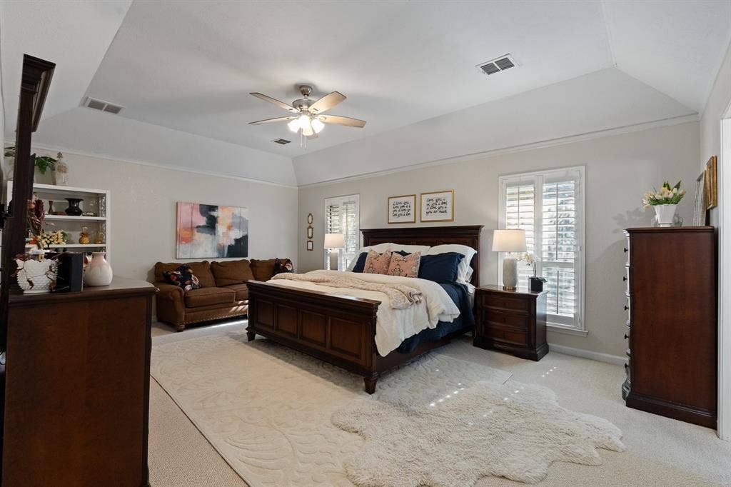 Tray ceiling with ceiling fan, two windows with plantation shutters, and recessed lighting