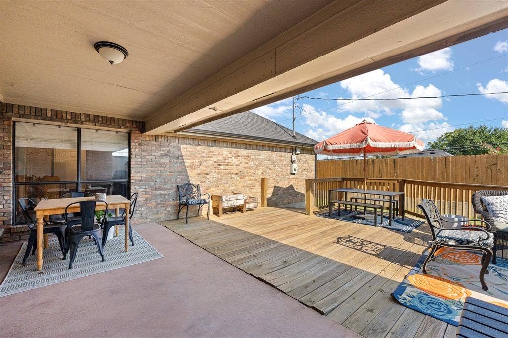 Covered patio with brick siding, a built-in wood deck, and a wood privacy fence