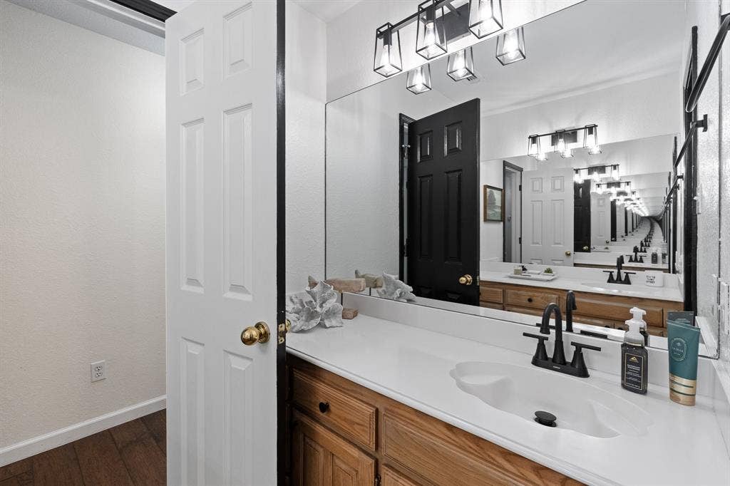 Vanity with a white countertop and integrated sink, wood-finish cabinetry, and a matte black faucet