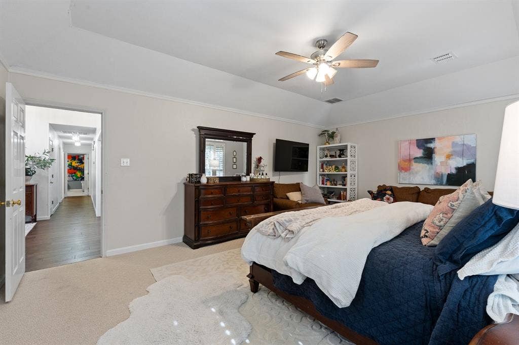 Tray ceiling with a ceiling fan, light-colored carpeting, and crown molding