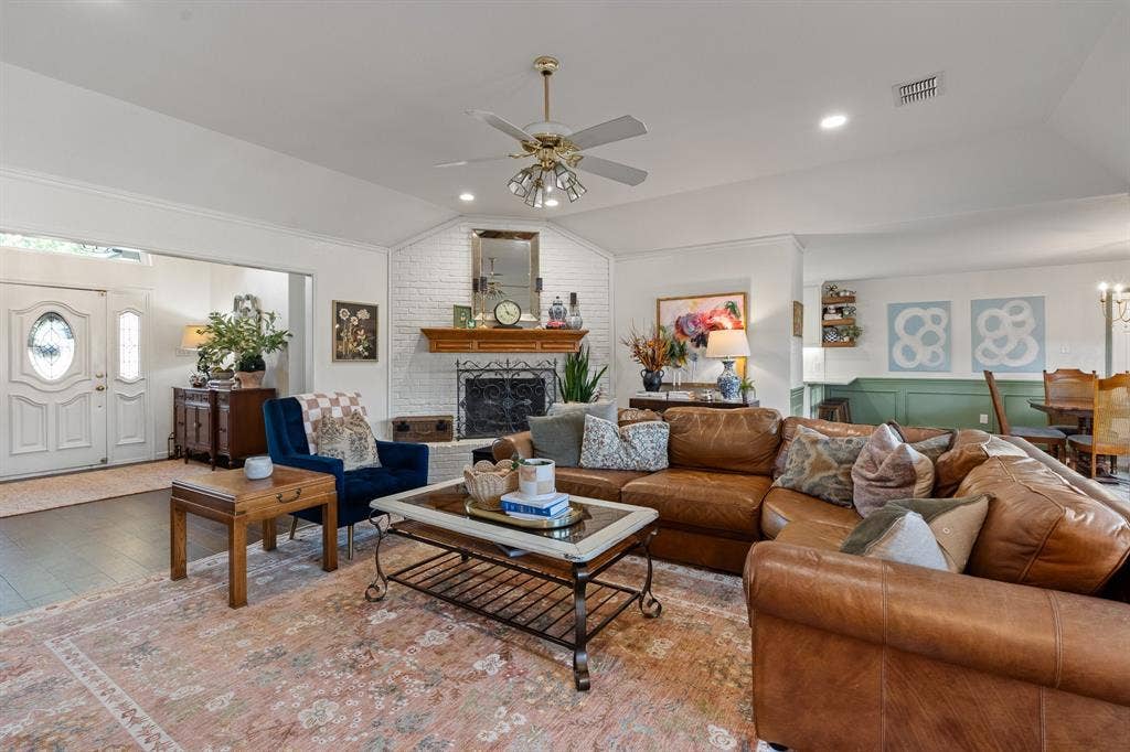 Vaulted ceiling, recessed lighting, ceiling fan, brick-clad fireplace with wood mantel, and wood flooring