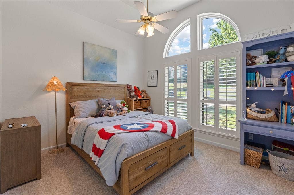 Arched windows with plantation shutters with built-in storage, and a ceiling fan
