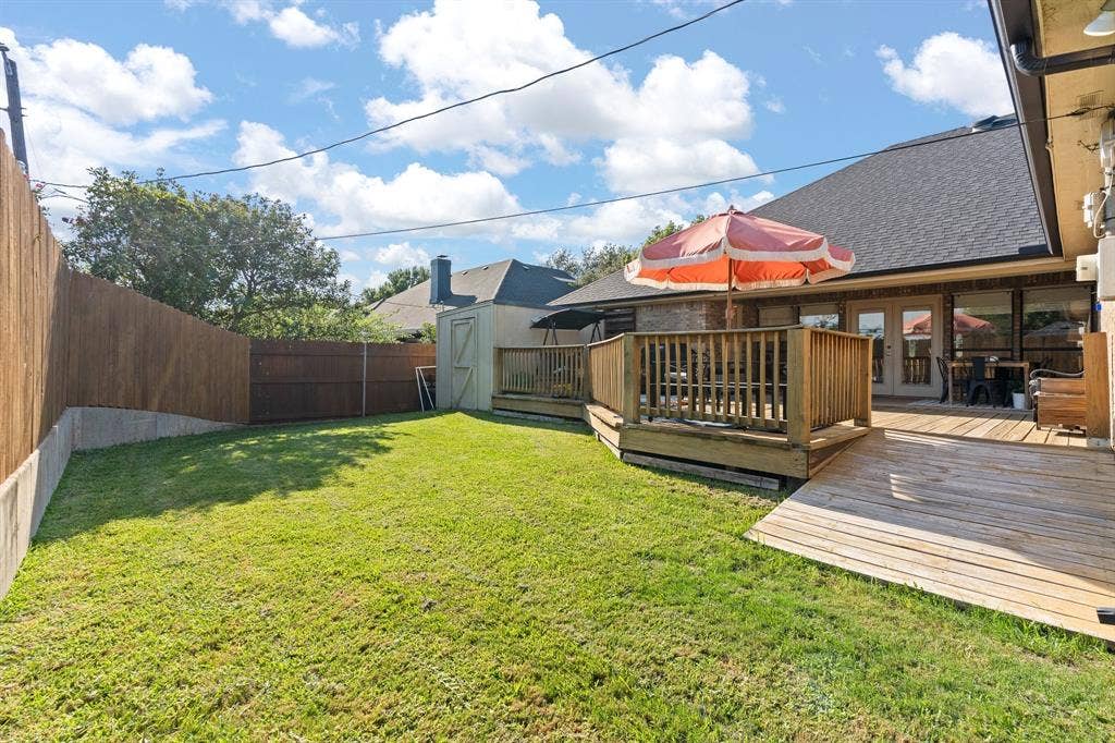 Expansive backyard featuring a manicured lawn, wood privacy fencing, and a multi-level wooden deck with a ramp