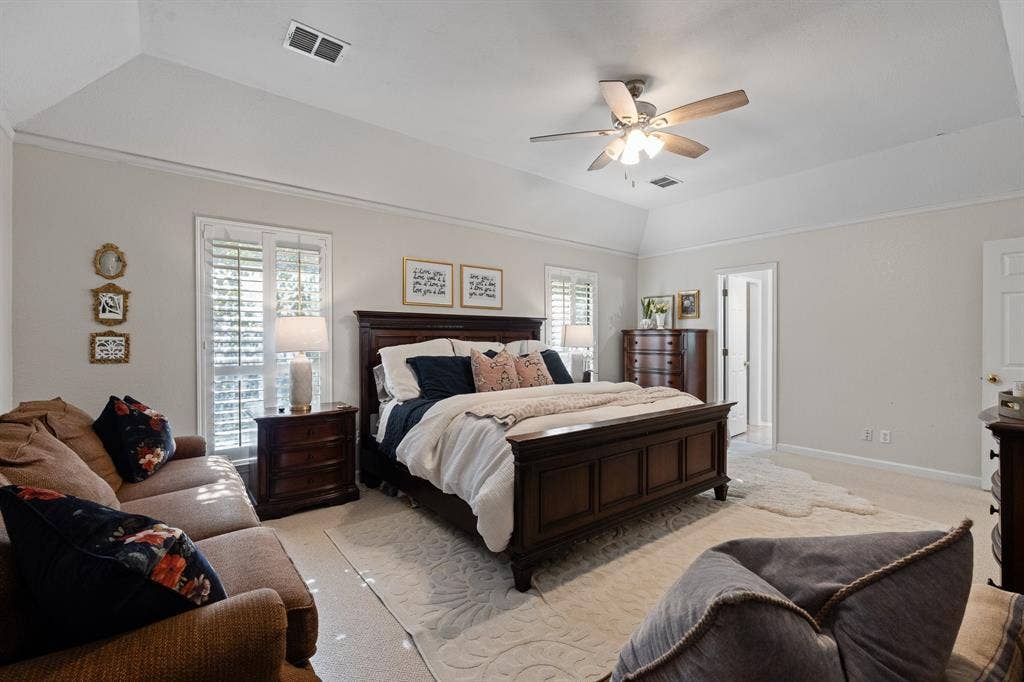 Tray ceiling with a ceiling fan light fixture, white plantation shutters, and light neutral wall paint