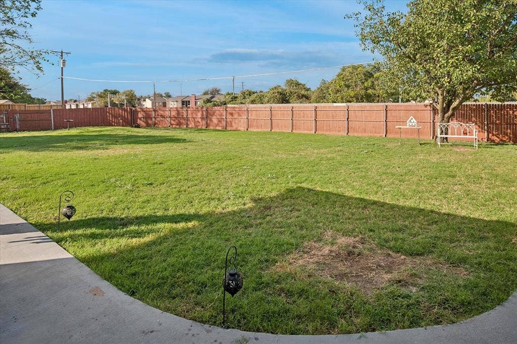 10102 Laingtree Drive, Dallas, TX 75243 Expansive backyard featuring a concrete patio, a full-perimeter wood privacy fence, and mature trees