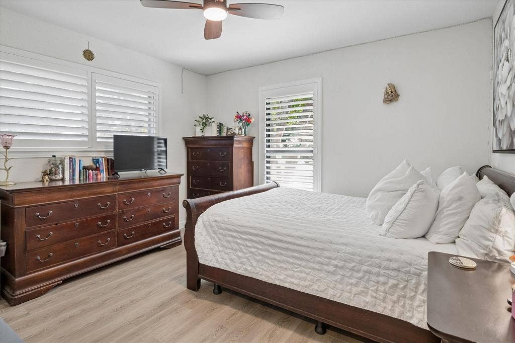 10102 Laingtree Drive, Dallas, TX 75243 Wood-finish flooring, multi-pane windows with integrated white plantation shutters, and a ceiling-mounted light fixture with fan