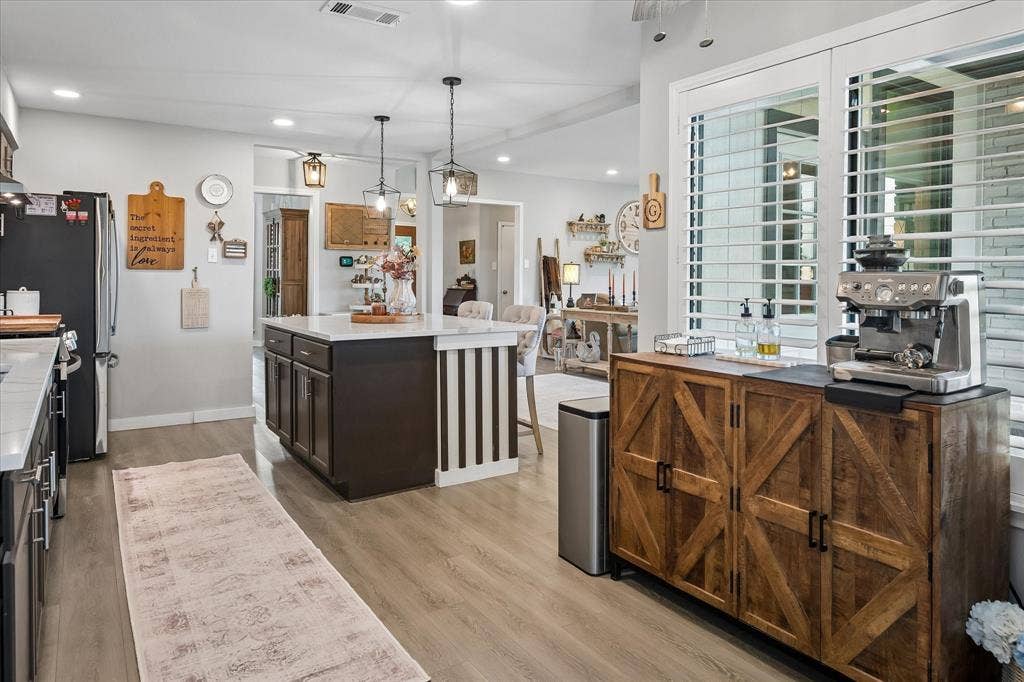 10102 Laingtree Drive, Dallas, TX 75243 Kitchen featuring a central island with a stone countertop, dark-finish cabinetry, recessed lighting, and wood-finish flooring