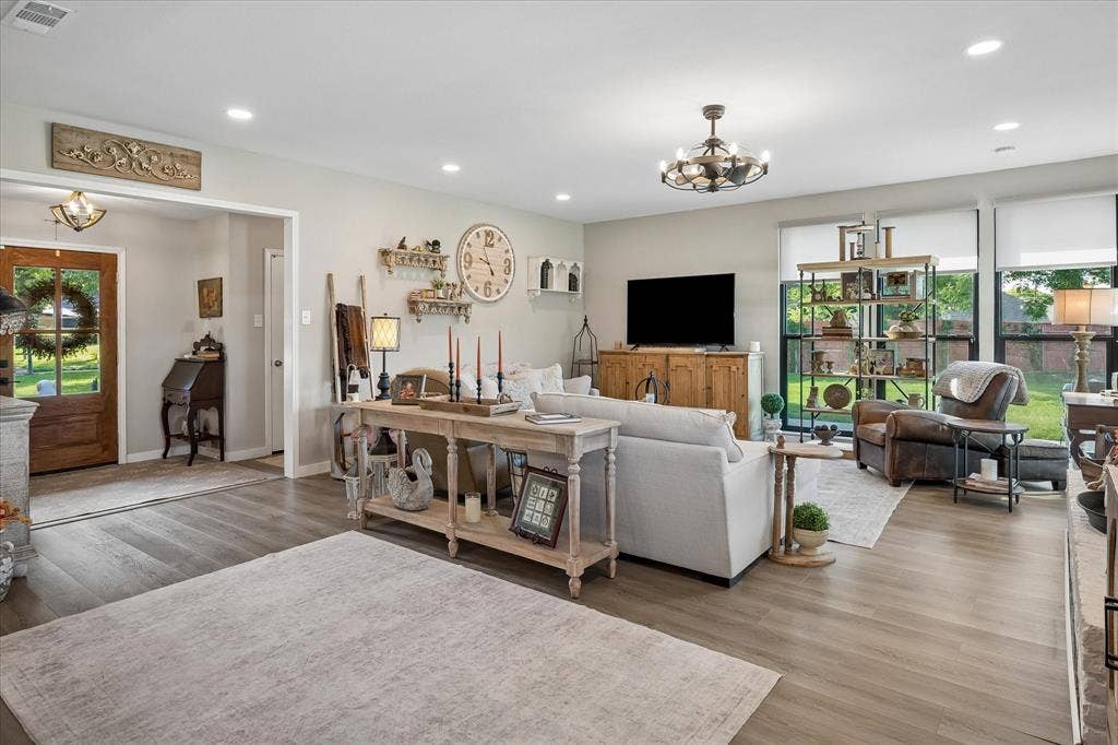 10102 Laingtree Drive, Dallas, TX 75243 Open-concept living space featuring wood-finish flooring, recessed lighting, a multi-light chandelier, and large windows with integrated shades
