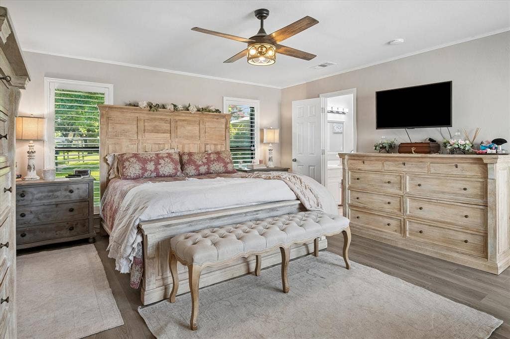 10102 Laingtree Drive, Dallas, TX 75243 Bedroom featuring wood-finish flooring, a multi-blade ceiling fan with integrated lighting, dual windows with plantation shutters, and six-panel interior doors