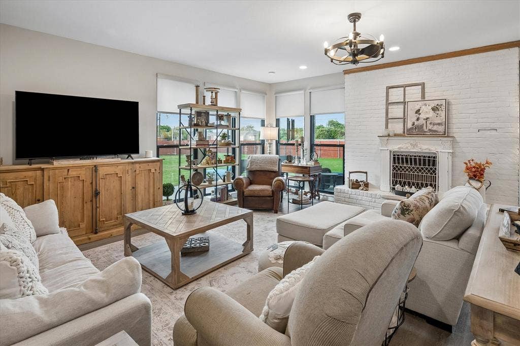10102 Laingtree Drive, Dallas, TX 75243 Living area featuring a floor-to-ceiling painted brick fireplace, built-in wooden media cabinetry, recessed lighting, and expansive windows