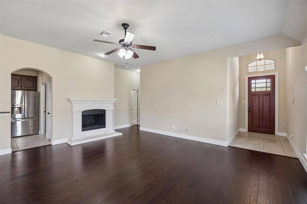 901 Memory Lane, McKinney, TX 75072 Spacious living area featuring dark engineered wood flooring, a white mantel gas fireplace, and a ceiling fan