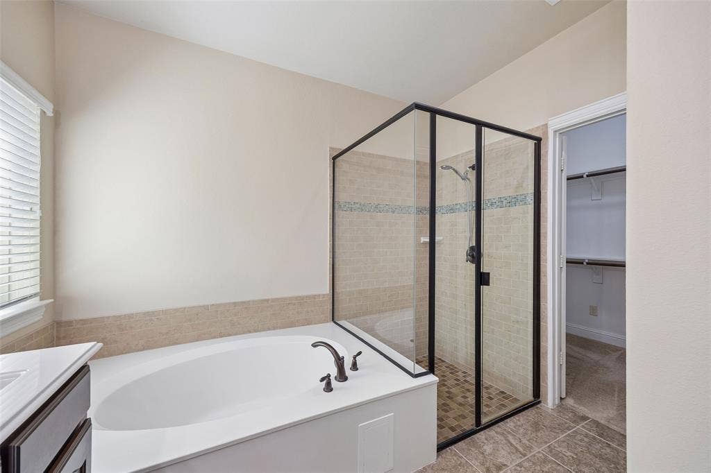 901 Memory Lane, McKinney, TX 75072 Soaking tub with bronze-finish fixtures, glass-enclosed shower with tiled walls and floor, and a built-in closet with shelving