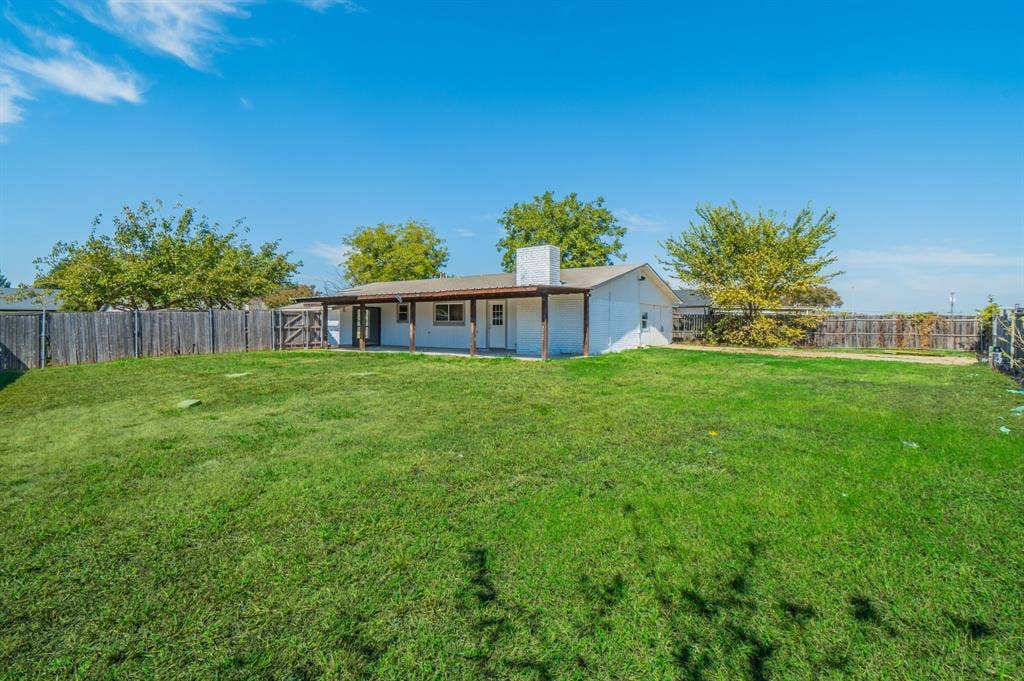 4312 Woodbluff Drive, Mesquite, TX 75150 Expansive grassy yard with wood fencing and a covered patio