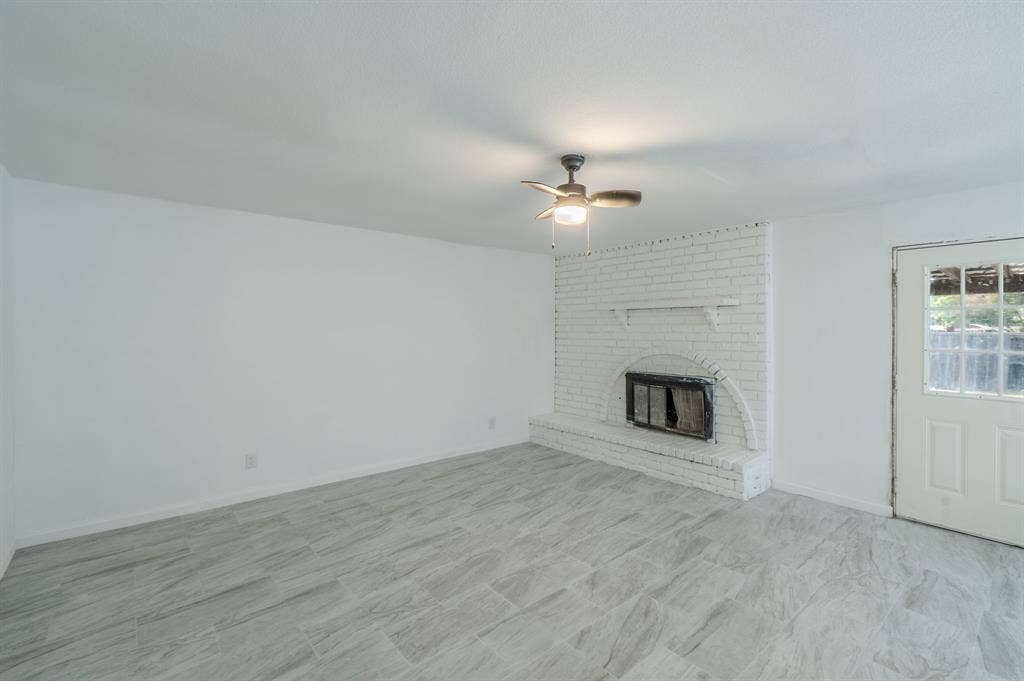 4312 Woodbluff Drive, Mesquite, TX 75150 White brick fireplace with hearth, wood-finish ceiling fan with integrated lighting, and light grey tile flooring