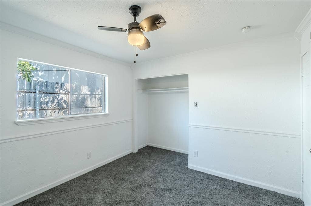 4312 Woodbluff Drive, Mesquite, TX 75150 Recessed open closet with clothing rod, textured white walls, window with privacy screen, ceiling fan, and dark gray carpet