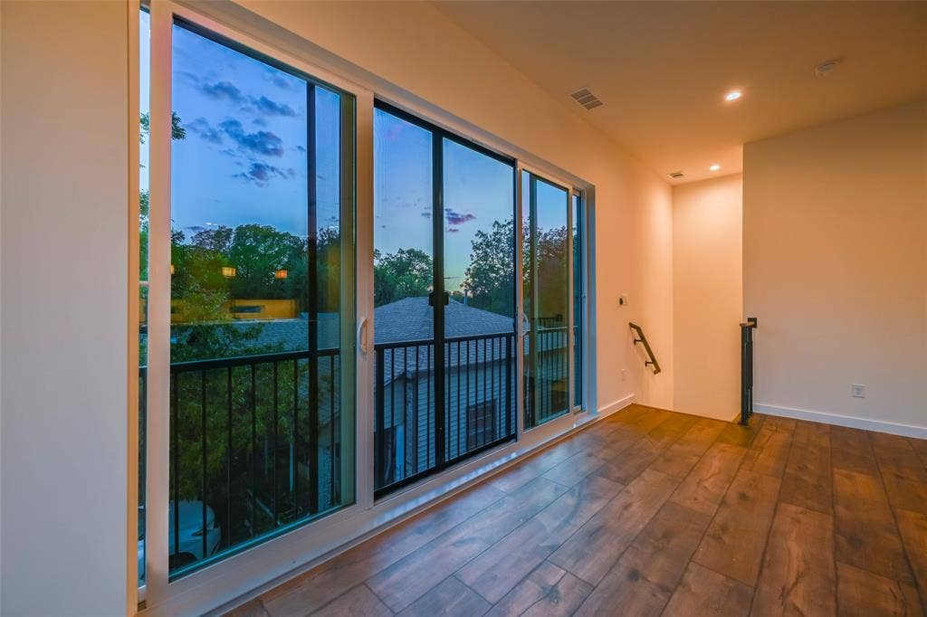 2247 Mail Avenue, #103, Dallas, TX 75235 Wood-finish flooring with a large sliding glass door opening to a private balcony with black metal railing