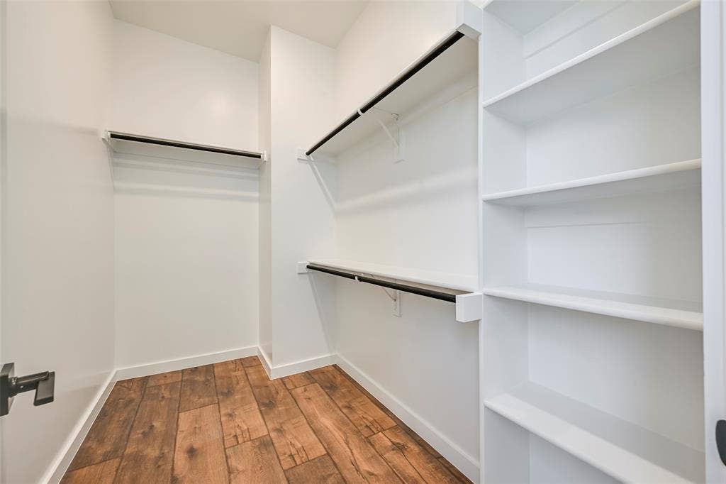 2247 Mail Avenue, #103, Dallas, TX 75235 Wood-finish flooring with white walls, multiple built-in shelving units, and black clothing rods