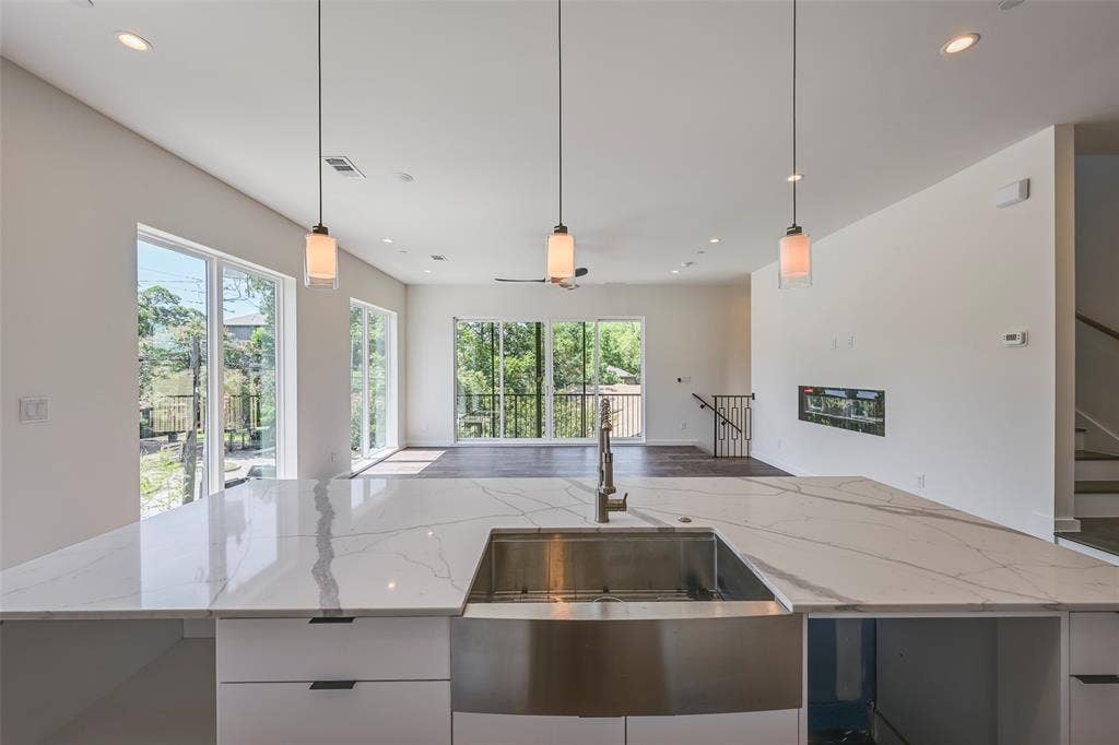2247 Mail Avenue, #103, Dallas, TX 75235 Expansive kitchen island with a waterfall edge, integrated stainless steel farmhouse sink, and three pendant lights