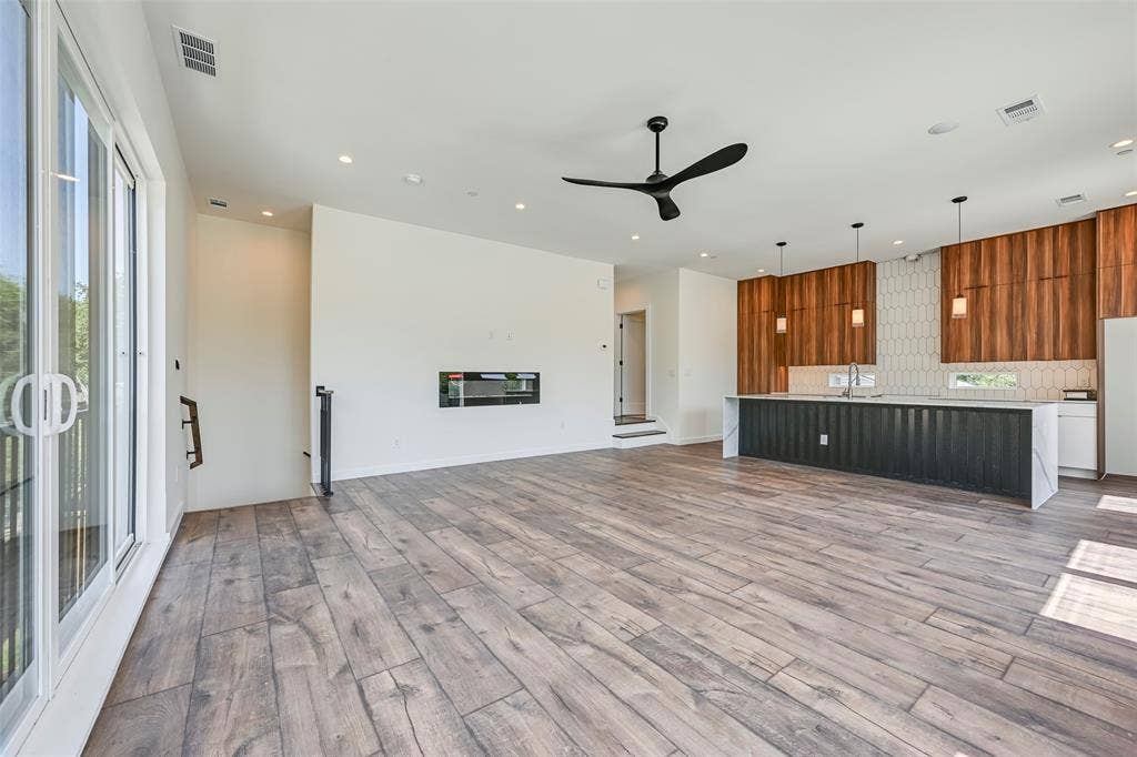 2247 Mail Avenue, #103, Dallas, TX 75235 Spacious open-concept living area featuring wood-finish flooring, a linear electric fireplace, and a modern ceiling fan