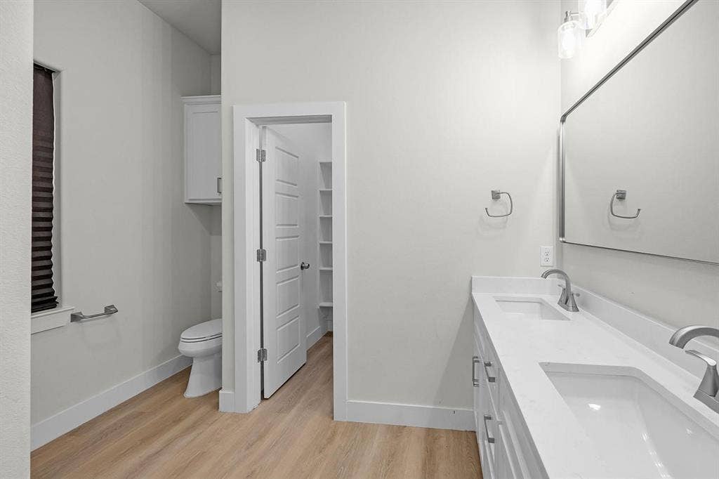 5511 Black Pine Circle, Granbury, TX 76048 Double vanity with integrated sinks, wood-finish flooring, a wall-mounted medicine cabinet, and built-in shelving